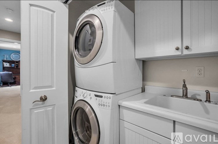 A white washing machine is stacked on top of a white dryer in a laundry room.