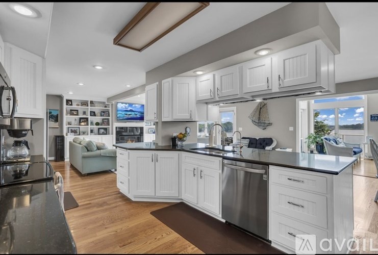 A modern kitchen with white cabinets and a wooden floor.