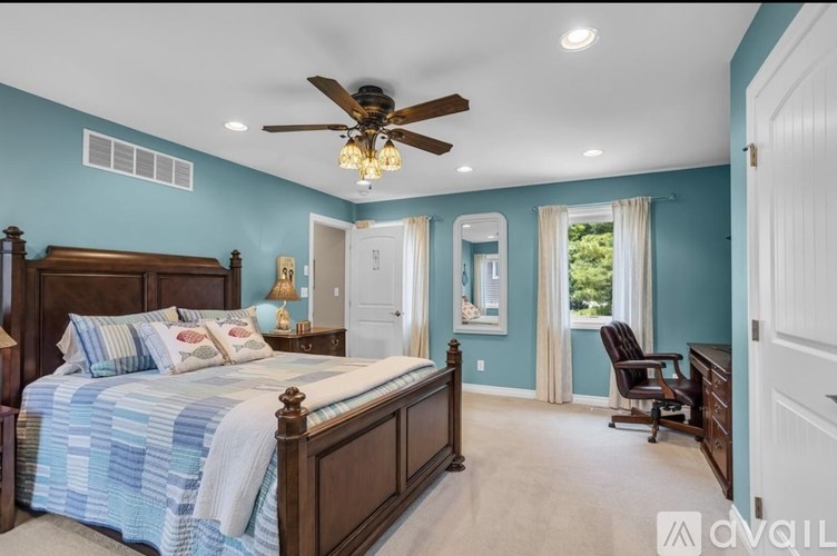 A bedroom with a bed, chair, and a ceiling fan.