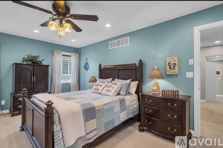 A bedroom with a bed, dresser, and ceiling fan.