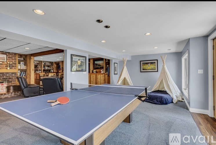 A ping pong table is in the middle of a room with a bed and a teepee.