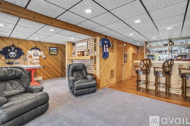A room with leather chairs and a wooden wall with Buffalo Bills memorabilia.
