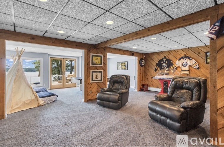 A room with a teepee, two leather chairs, and a hockey jersey on the wall.