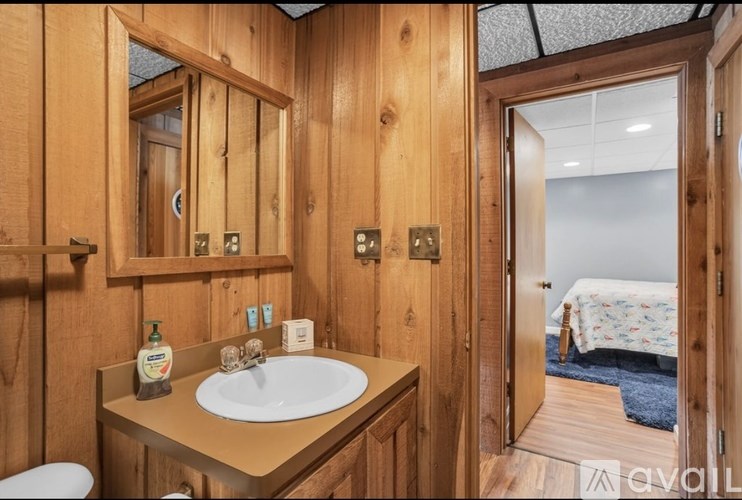 A wooden bathroom with a sink, mirror, and toilet.