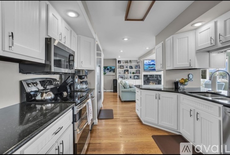 A modern kitchen with white cabinets and black countertops.
