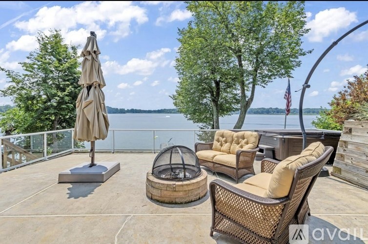 A patio with a table, chairs, and an umbrella overlooking a lake.