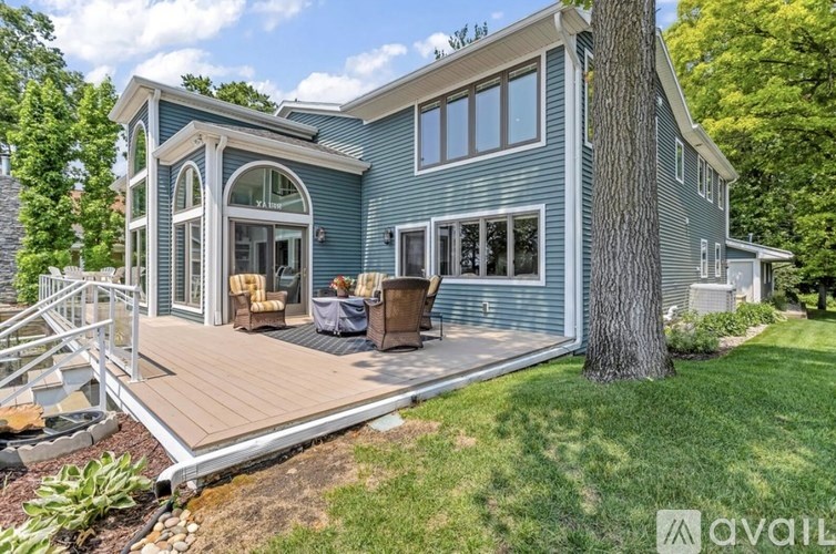 A house with a blue exterior and a deck with a table and chairs.