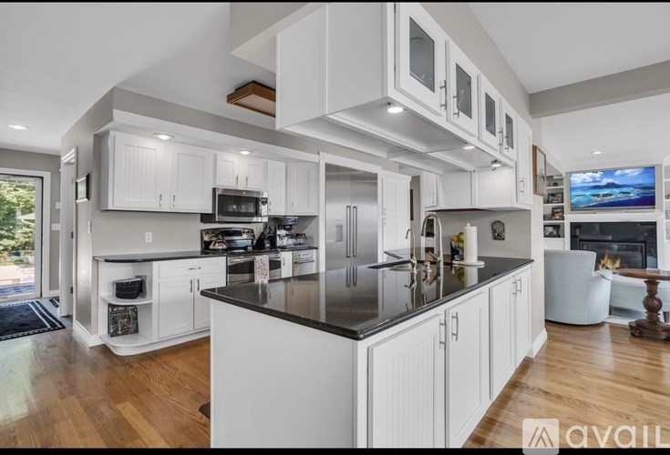 A modern kitchen with white cabinets and a black countertop.