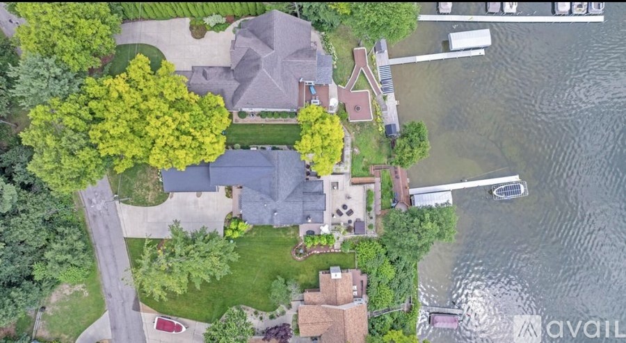 A house with a driveway and a boat in the water.