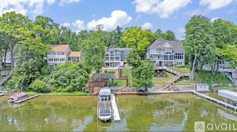 A house is surrounded by trees and is situated next to a body of water.