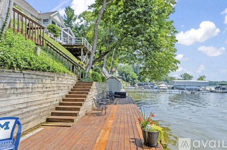 A wooden deck overlooks a body of water with a bench and a planter on it.