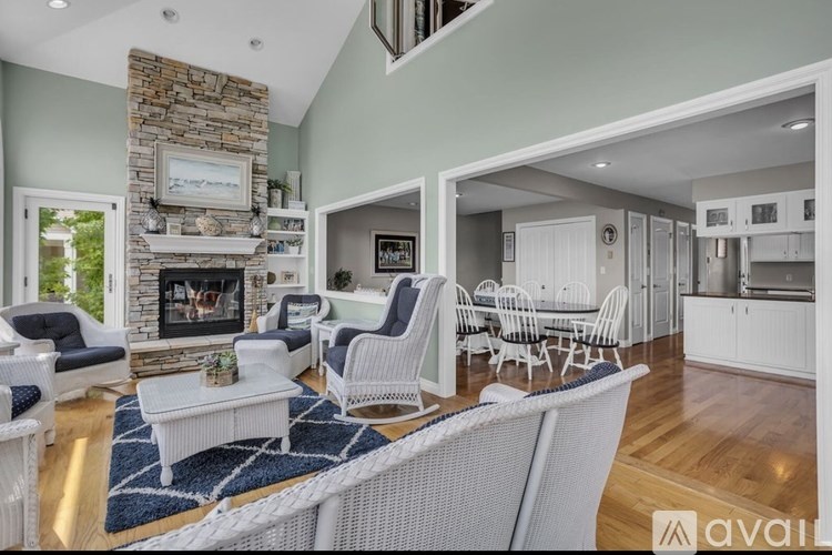 A living room with a stone fireplace and white furniture.