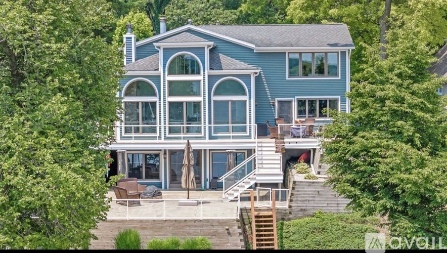 A large house with a deck and a staircase leading to the entrance.