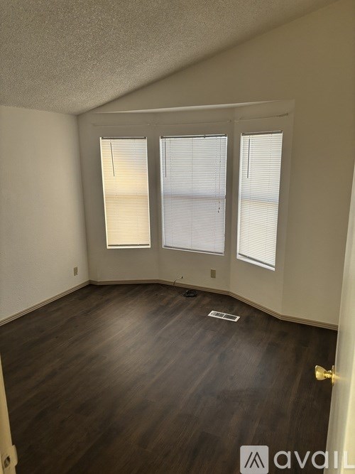 A room with wooden floors and a window with blinds.