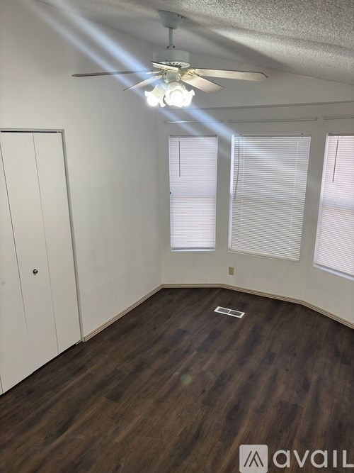 A room with a ceiling fan and wooden flooring.