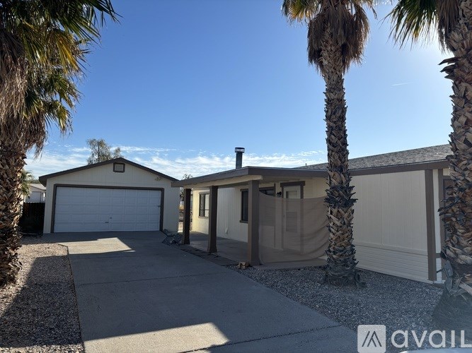 A house with a driveway and palm trees in front.