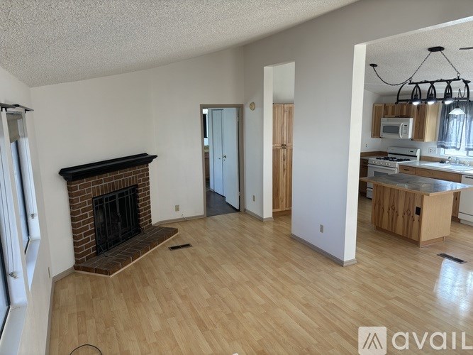 A living room with a fireplace and a kitchen in the background.