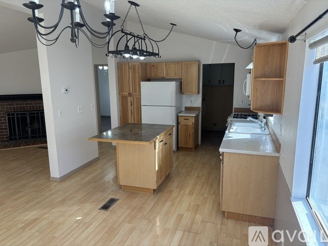 A kitchen with wooden floors and a white refrigerator.