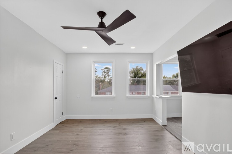 A room with a ceiling fan and two windows.