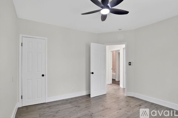 A room with a ceiling fan and two doors.