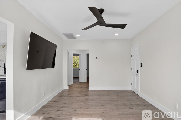 A spacious room with a ceiling fan and a flat screen TV mounted on the wall.