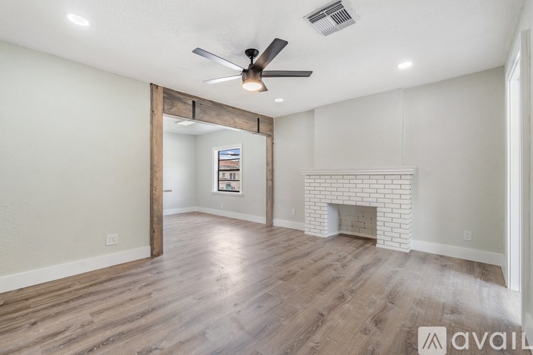 A spacious living room with a fireplace and a ceiling fan.