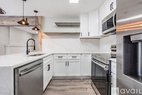 A modern kitchen with white cabinets and stainless steel appliances.