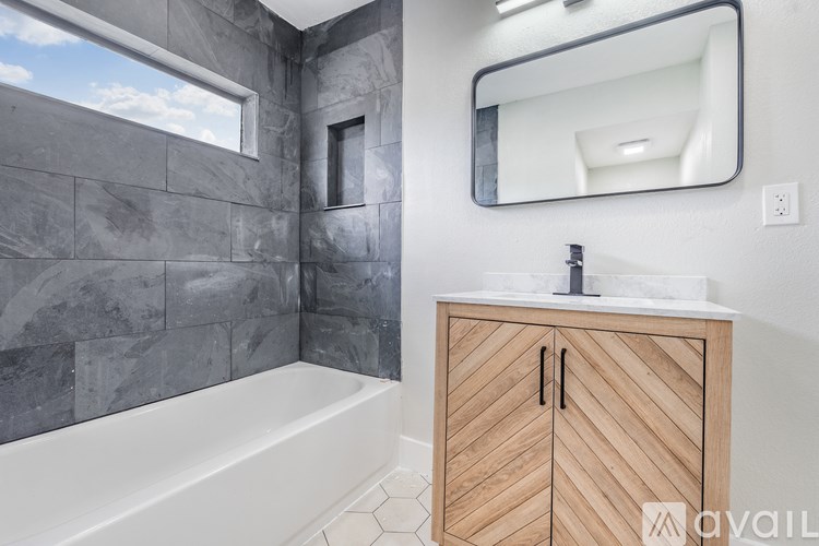 A bathroom with a tub, sink, and mirror.