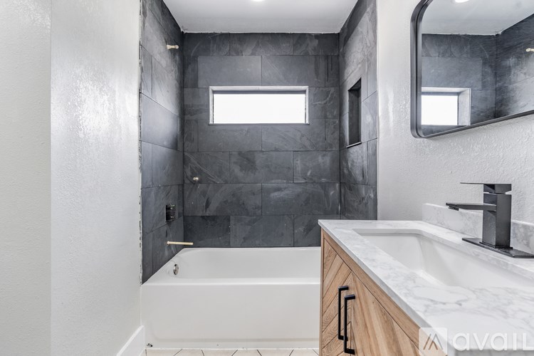 A modern bathroom with a white tub and sink.