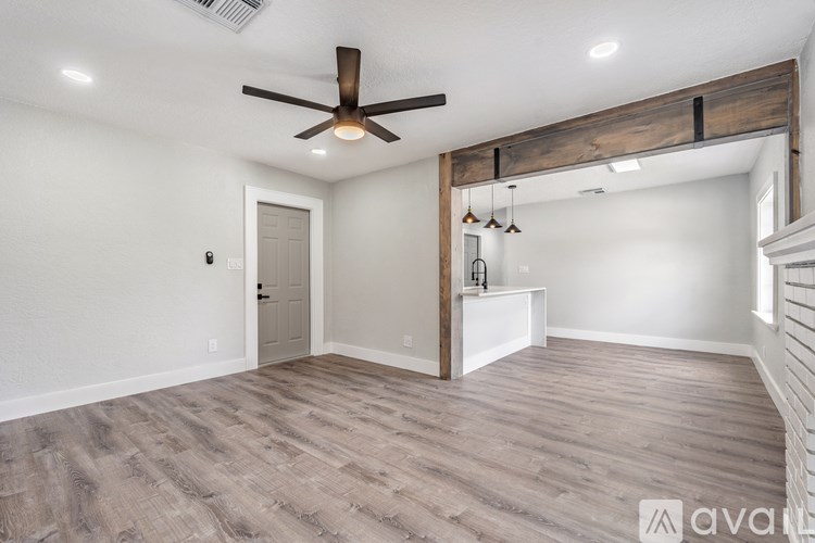 A spacious room with a ceiling fan and wooden beams.