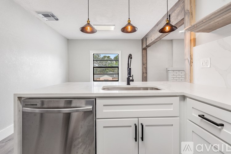 A kitchen with a stainless steel dishwasher and white cabinets.