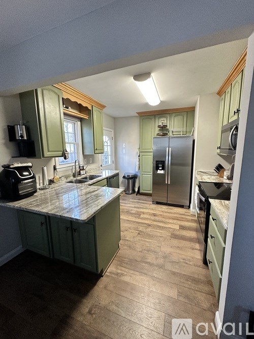 A kitchen with green cabinets and a wooden floor.