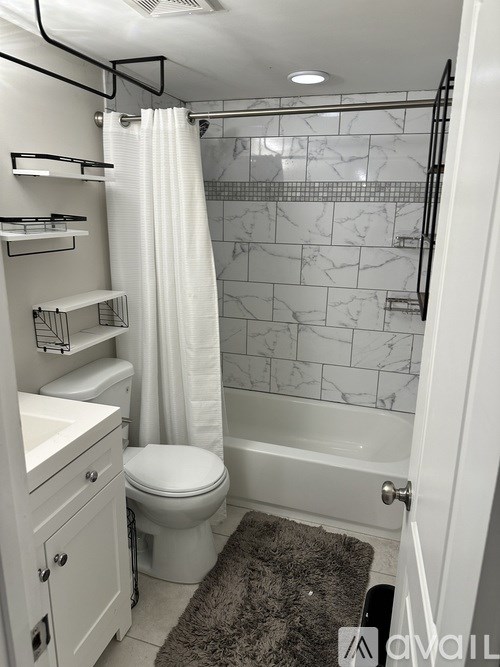A white bathroom with a toilet, sink, and shower.