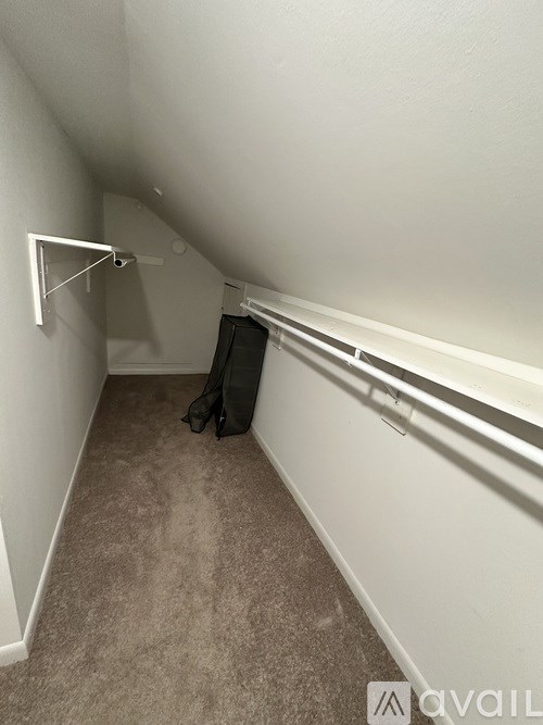 A small room with a carpeted floor and a black bag on the floor.