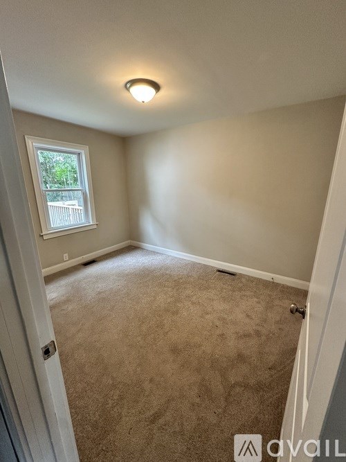 A room with a carpeted floor and a window.