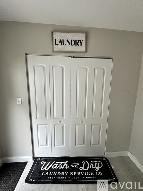 A laundry sign is above a door with a mat below that says Wash and Dry Laundry Service Co.