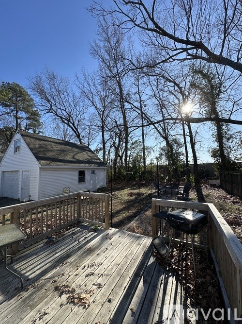 A deck with a grill and a white house in the background.