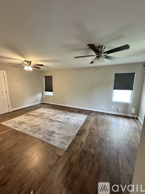 A room with a ceiling fan and a rug on the floor.