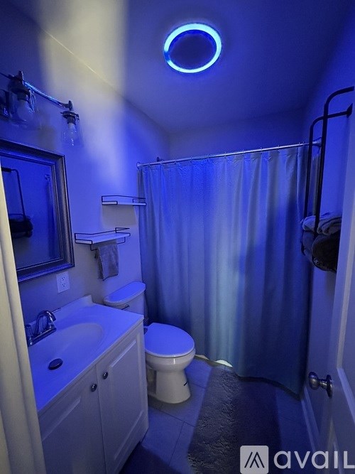 A bathroom with blue lighting and a white toilet.
