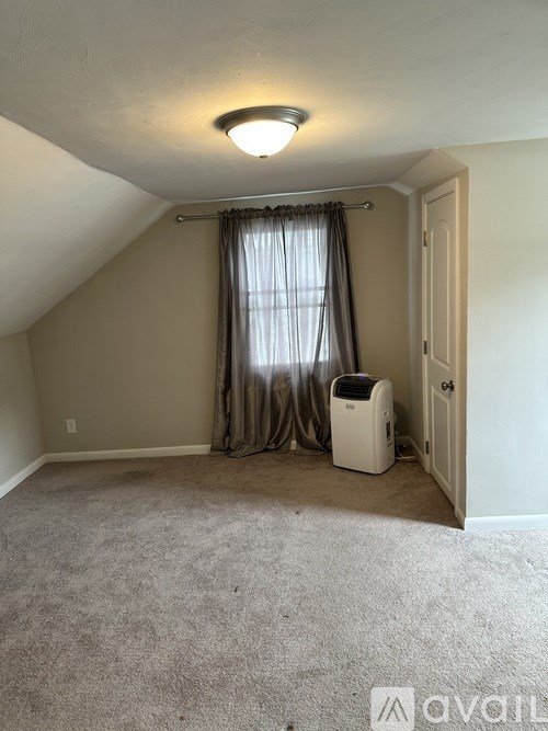 A room with a carpeted floor, a ceiling fan, and a window with curtains.