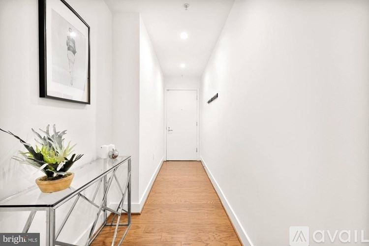 A long hallway with a glass table and a potted plant.