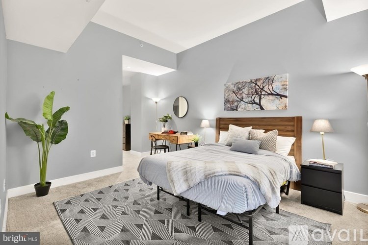 A bedroom with a bed, nightstand, and a potted plant.