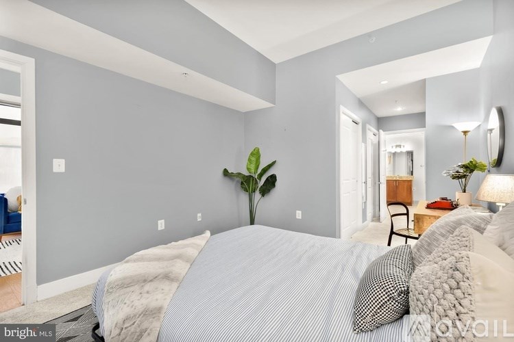 A bedroom with a bed, a chair, and a potted plant.