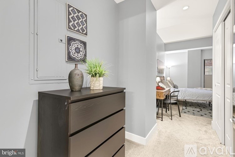 A bedroom with a bed, chair, and a dresser with a vase on top.