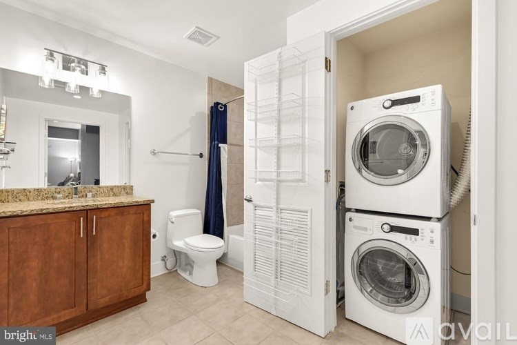 A bathroom with a washer and dryer in the doorway.