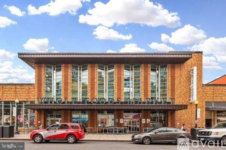 A red car is parked in front of a building with a sign that reads "Welcome".