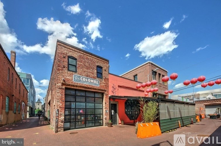 A building with a sign that says "COLUMBIA" is in the foreground with a blue sky and clouds in the background.