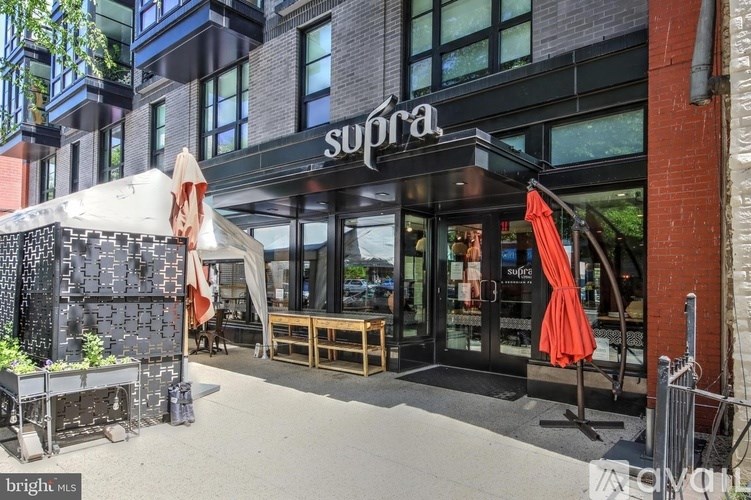The image shows a building with a black awning and the word "supra" written on it.