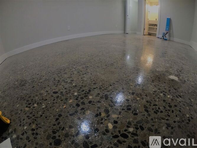 A room with a speckled floor and a door in the background.