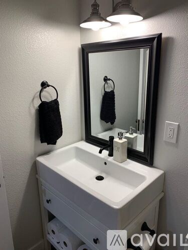 A white sink with a black mirror above it.